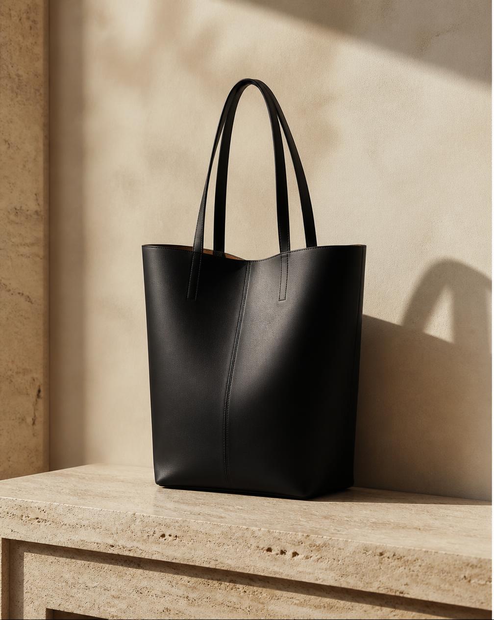 The Tote — black leather bag on travertine, coming soon