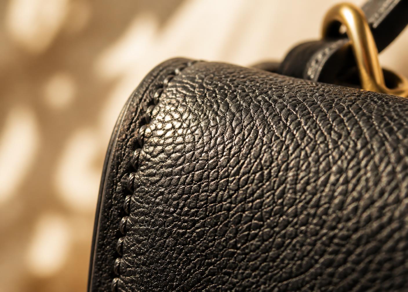 Macro detail of black leather grain and hand stitching